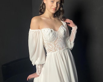 May include: A white off-the-shoulder wedding dress with a lace bodice and long, sheer sleeves. The dress features a flowing skirt with a high slit. The bodice is intricately detailed with floral lace patterns, creating an elegant and romantic look.