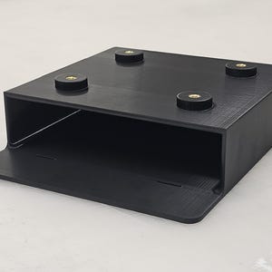 May include: Black plastic stand with four rubber feet. The stand has a raised platform and a lower shelf.