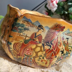 Könnte beinhalten: Eine dekorative Keramikschale mit goldgelber Craquelé-Glasur. Die Außenseite zeigt eine detaillierte handgemalte Szene mit Figuren in traditioneller Kleidung, einem Pferd sowie einer Landschaft mit Bergen und Kiefern in verschiedenen Rottönen.