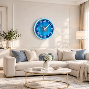 May include: A round wall clock with a blue and white resin finish, featuring a textured center and white Roman numerals. The clock has silver-toned hour, minute, and second hands, and a smooth, irregular edge that mimics the appearance of a geode.