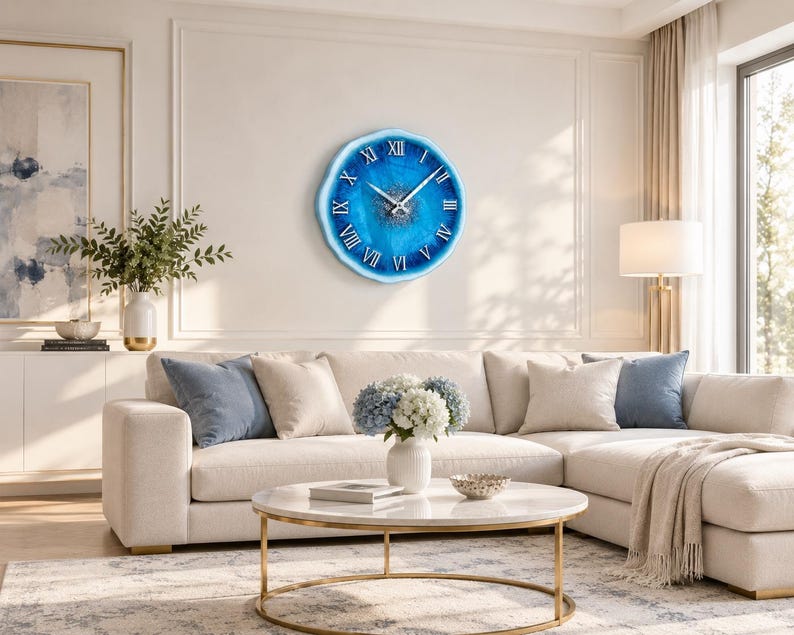 May include: A round wall clock with a blue and white resin finish, featuring a textured center and white Roman numerals. The clock has silver-toned hour, minute, and second hands, and a smooth, irregular edge that mimics the appearance of a geode.