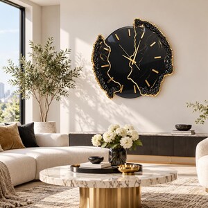 Pu&ograve; includere: Un grande orologio da parete circolare con quadrante nero lucido, lancette dorate e indici delle ore dorati. L'orologio presenta un bordo fratturato ispirato alle geodi, con bordi neri testurizzati e accenti color oro dall'aspetto organico.