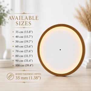 May include: A circular wall clock with a brown wooden frame and a white face featuring an internal warm light ring. Text lists available sizes from 35 cm (13.8 inches) to 100 cm (39.4 inches) and a board thickness of 35 mm (1.38 inches).