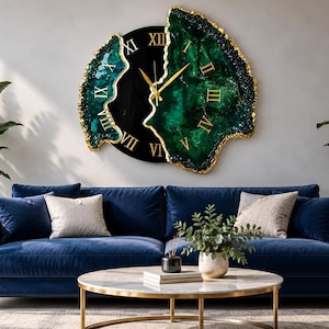 Puede incluir: Un reloj de pared con un centro circular negro y dos secciones irregulares de color verde esmeralda inspiradas en geodas, con bordes pintados en oro. La esfera muestra n&uacute;meros romanos dorados y finas manecillas doradas.