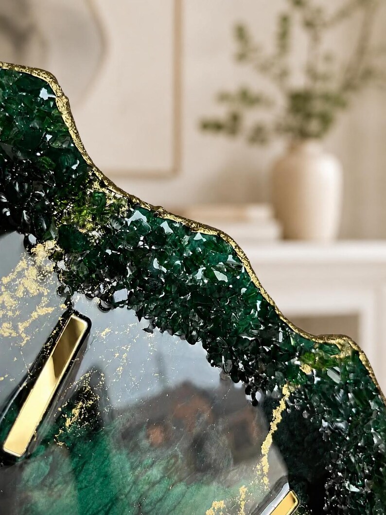 May include: A decorative tray featuring a dark green resin surface with embedded crystalline textures along the irregular, gold-leafed edges. The smooth center displays swirling dark green and black tones with scattered gold flakes and metallic gold accents.