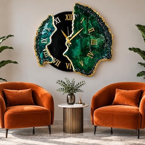 Puede incluir: Un gran reloj de pared con un centro circular negro, n&uacute;meros romanos dorados y dos secciones laterales de resina verde esmeralda con bordes pintados en oro. El reloj tiene manecillas doradas y una forma irregular inspirada en una geoda.