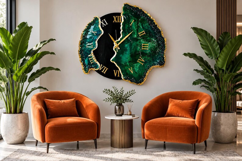 Puede incluir: Un gran reloj de pared con un centro circular negro, n&uacute;meros romanos dorados y dos secciones laterales de resina verde esmeralda con bordes pintados en oro. El reloj tiene manecillas doradas y una forma irregular inspirada en una geoda.