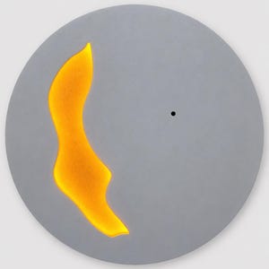 May include: A circular gray wall clock with a smooth matte finish. The clock face features a single small black dot at the center and a large, irregular, flame-shaped cutout on the left side that glows with a bright, vibrant orange light.