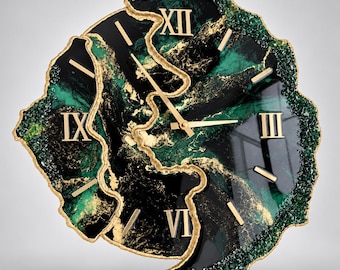 Può includere: Un orologio da parete dalla forma irregolare ispirata a una geode, con una superficie marmorizzata nero lucido e verde smeraldo con accenti dorati. Il quadrante presenta numeri romani dorati alle posizioni delle tre, sei, nove e dodici.