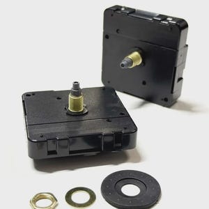 May include: Two black clock movements with gold-colored shafts and a set of hardware. The hardware includes a gold-colored nut, a gold-colored washer, and a black rubber washer. The clock movements are square and have a plastic casing.