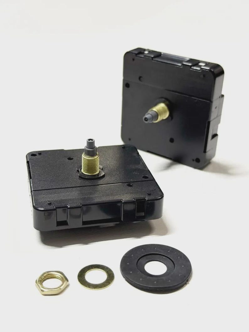 May include: Two black clock movements with gold-colored shafts and a set of hardware. The hardware includes a gold-colored nut, a gold-colored washer, and a black rubber washer. The clock movements are square and have a plastic casing.
