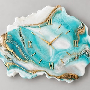 May include: An irregular, geode-shaped wall clock featuring a swirling blend of turquoise, white, and gold resin. The clock face includes gold-colored Roman numerals at the twelve, three, six, and nine o'clock positions, with gold hands.