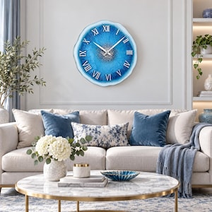 May include: A circular wall clock with an irregular, wavy edge featuring a vibrant blue resin finish with a central silver glitter accent. The clock face displays white Roman numerals and two thin white hands for hour and minute tracking.