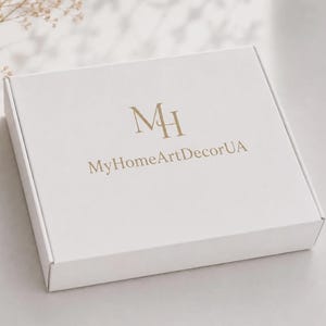 May include: A square white cardboard shipping box featuring the gold-colored logo MH and the text MyHomeArtDecorUA printed on the top surface. The box is closed and has a clean, matte finish with sharp edges and a standard folding design.