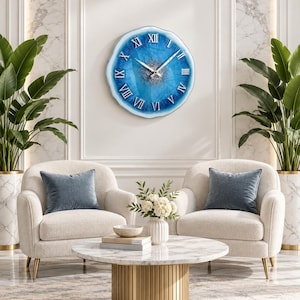 May include: A round wall clock with an irregular, geode-inspired edge featuring a vibrant blue resin face, silver glitter accents in the center, and raised silver Roman numerals. The clock has two thin silver hands and a glossy, smooth finish.