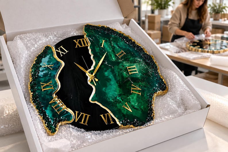 Puede incluir: Un reloj de pared con dise&ntilde;o dividido, centro negro y bordes de resina veteada en verde oscuro. El reloj tiene n&uacute;meros romanos dorados y manecillas a juego. Los bordes exteriores est&aacute;n texturizados con un acabado pintado en oro.