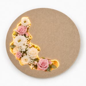 May include: A circular beige wooden plaque featuring a crescent-shaped cutout filled with an arrangement of white and pink roses, eustoma flowers, and small white filler blossoms, illuminated from within by a warm yellow LED light strip.