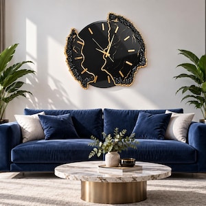 Pu&ograve; includere: Un orologio da parete circolare con quadrante nero, indici e lancette color oro. L'orologio presenta un bordo irregolare ispirato alle geodi, con texture nere e dorate che incorniciano la superficie centrale nera con venature sottili.