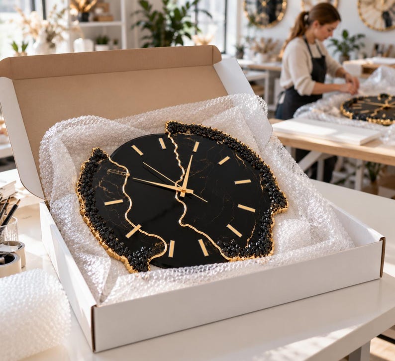 Pu&ograve; includere: Un orologio da parete rotondo con quadrante effetto marmo nero, lancette dorate e indicatori delle ore dorati. L'orologio presenta un design frastagliato e diviso al centro, con bordi neri e dorati testurizzati all'interno di una scatola.