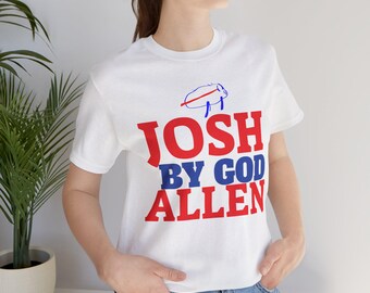 May include: White t-shirt with red and blue text that reads "Josh By God Allen". A small drawing of a pig is above the text.