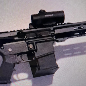 May include: A black rifle with a black scope mounted on top. The rifle has a black magazine attached to the bottom.