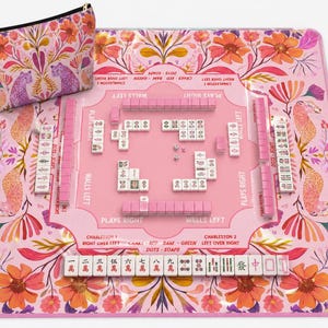 May include: A pink Mahjong set with matching floral design mat and zippered pouch. The set includes pink tiles, dice, and tile racks. The mat features floral and leopard print designs, with text indicating game play directions.
