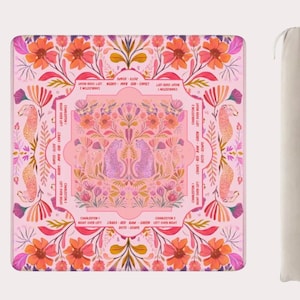 Op de afbeelding: Een roze vierkante mat met een bloemenontwerp en zeepaardillustraties. De mat heeft een centraal ontwerp van twee cheeta's en tekst rond de rand. Een beige draagtas staat naast de mat.