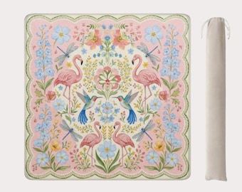 May include: A square picnic blanket with a pink floral design featuring flamingos, hummingbirds, and dragonflies. The blanket has a scalloped edge and comes with a beige carrying case.