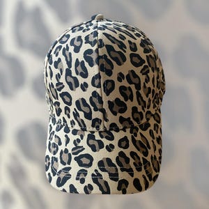 Könnte beinhalten: Eine Baseballkappe mit einem gekrümmten Schirm in brauner und schwarzer Leopardenmuster.