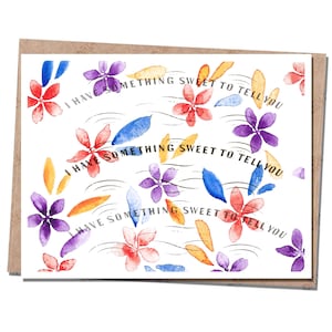 May include: A white card with a watercolor floral pattern in shades of red, purple, blue, and yellow. The text "I have something sweet to tell you" is repeated three times in black.