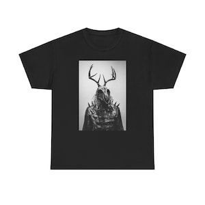 May include: Black and white graphic t-shirt featuring a creature with antlers and a skull-like mask. The creature is wearing a dark, spiky garment.