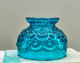 May include: A vibrant turquoise blue glass bowl featuring a raised moon and star pattern with a scalloped rim. The bowl rests on a book titled The Life-Changing Magic of Tidying Up by Kondo, which has a watercolor-style cover design.