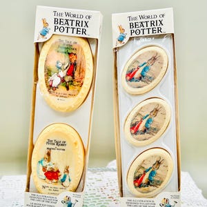 May include: Two boxed sets of Beatrix Potter soaps. One box features oval soaps with illustrations from "The Tale of Peter Rabbit" and "The Tale of Jemima Puddle-Duck." The other box contains three oval soaps with Peter Rabbit illustrations.