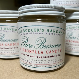 May include: Several glass jars of Pure Beeswax Citronella Candles with white lids and labels. The labels read "Pure Beeswax Citronella Candle" and "With Ten Anti-Bug Essential Oils". The jars are made in Clawson, Michigan.