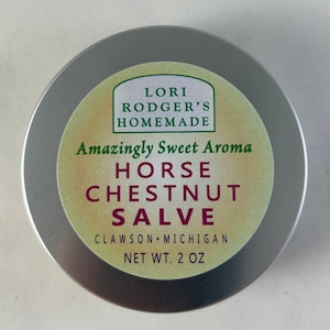 May include: A round, silver-colored tin of Lori Rodger's Homemade Horse Chestnut Salve. The label features green and tan colors with text that reads "Amazingly Sweet Aroma" and "NET WT. 2 OZ."