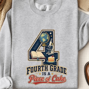 May include: A light gray crewneck sweatshirt featuring a large graphic of the number 4. Inside the number are illustrations of a globe, a microscope, an open book, and a slice of cake. Below the graphic is the text Fourth Grade is a Piece of Cake.