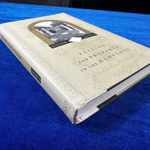 May include: A white hardcover book with the title "Passion and Property in the Hamptons" by Steven Gaines. The book cover features a black and white photograph of a building with columns.