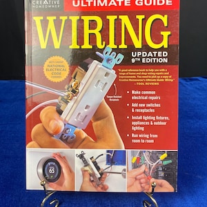 May include: The cover of a book titled "Ultimate Guide Wiring" by Creative Homeowner. The book features a close-up of electrical wiring components and the text "Updated 9th Edition". The book also includes a thermostat with a display of 65.