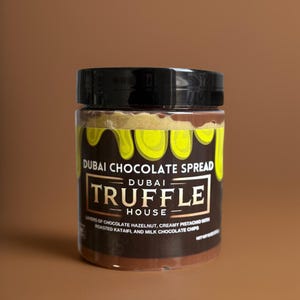 May include: A jar of Dubai Chocolate Spread with a black lid. The label features the text "Dubai Chocolate Spread" and "Truffle House". Ingredients include chocolate hazelnut, creamy pistachio, roasted kataifi, and milk chocolate chips.
