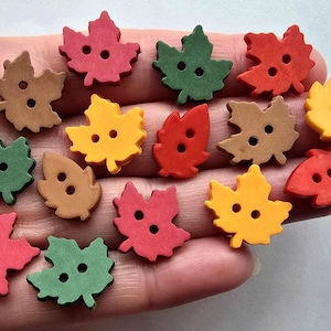 May include: A selection of leaf-shaped buttons in autumnal shades of red, green, yellow, and brown. Each button features two holes for sewing. These decorative buttons are perfect for craft projects.