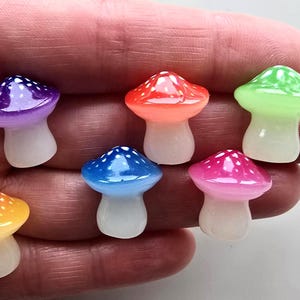 May include: Seven miniature mushroom ornaments in a variety of colours. Each mushroom has a white stem and a cap in shades of purple, red, green, blue, pink, and yellow, with white polka dots. The figurines are small and appear glossy.