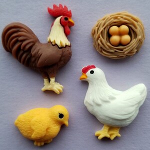 May include: A set of farm-themed decorations. Features a brown cockerel with a red comb, a white hen with a red comb, a yellow chick, and a nest with four eggs. The figures are detailed and colourful.