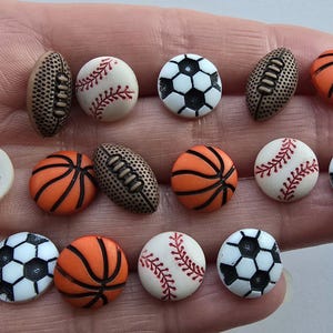Peut inclure: Assortiment de 14 boutons en plastique colorés sur le thème du sport, dont le baseball, le basketball, le football américain et le football.