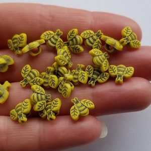 May include: A collection of yellow plastic buttons shaped like bees. The buttons have black details and are perfect for sewing projects.