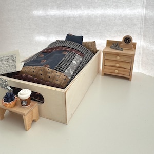 May include: Miniature bedroom set with a wooden bed frame, patterned bedding, and a small nightstand. The bed has a patchwork quilt with various fabric patterns. A tiny table holds a pastry and coffee cup.
