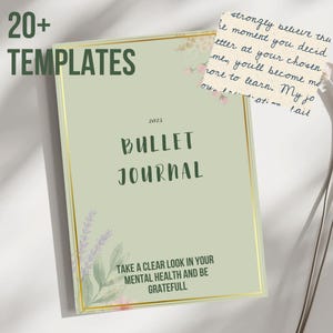 Op de afbeelding: Een saliegroen bullet journal met gouden rand en de tekst "Bullet Journal" in een handgeschreven lettertype. De cover bevat ook de tekst "20+ Templates" en "Take a clear look in your mental health and be grateful". Een kleine notitie met handgeschreven tekst is zichtbaar.