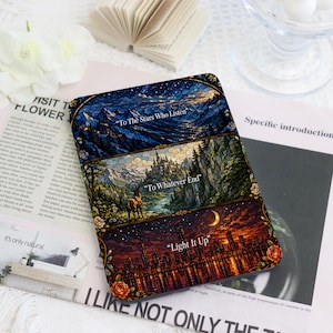 Puede incluir: Una funda rectangular para lector electrónico con un diseño de estilo vidriera dividido en tres paneles horizontales. El panel superior muestra un paisaje montañoso azul oscuro con el texto "To The Stars Who Listen". El panel central representa un castillo, un bosque y un ciervo con el texto "To Whatever End". El panel inferior muestra el horizonte de una ciudad de noche con el texto "Light It Up".