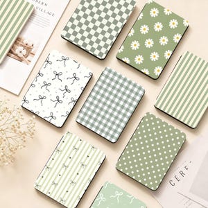 Peut inclure: Une collection de carnets rectangulaires présentant divers motifs, notamment des damiers vert sauge et blanc, des fleurs marguerites, des nœuds noirs sur fond blanc, du vichy vert, des rayures verticales et des pois blancs sur fond vert sauge.