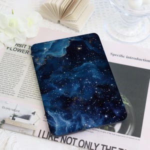 May include: A rectangular, dark blue decorative item with a celestial design featuring swirling nebulas and numerous white stars. The item has a glossy finish and is placed on a light-colored surface. The text "I LIKE NOT ONLY THE" is visible.