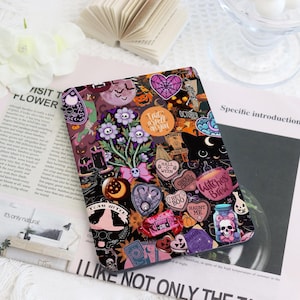 Può includere: Una custodia per tablet nera con un collage di adesivi a tema Halloween. Gli adesivi includono un bouquet di fiori viola, un gatto nero, un teschio e le parole "I put a spell on you".